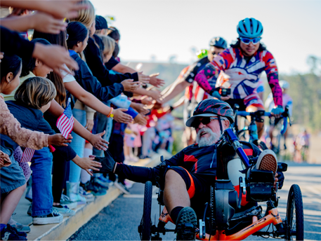 A group of cyclists high fiving spectators.